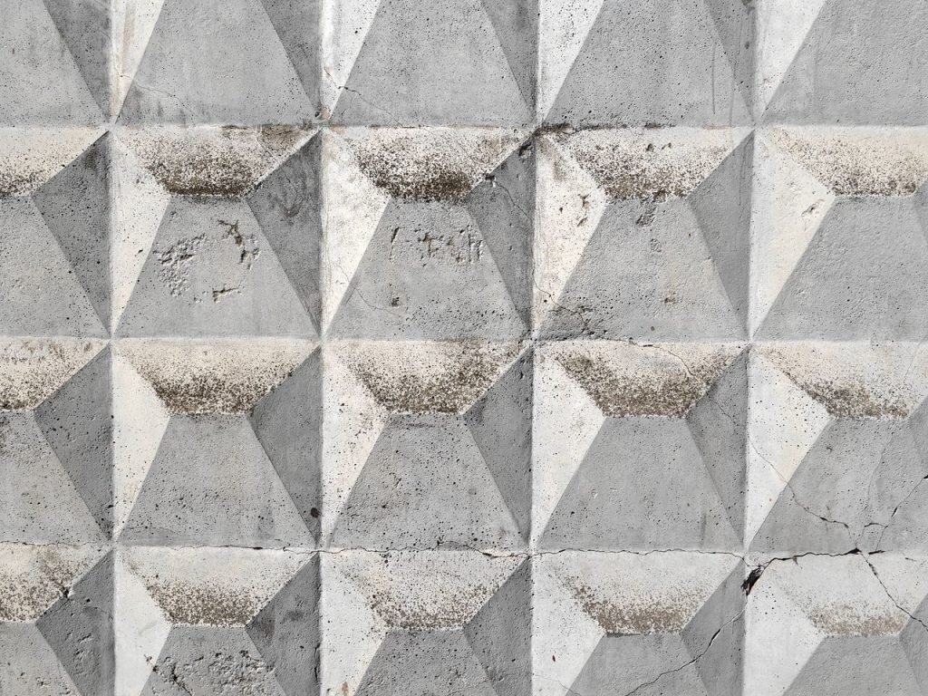 The Art of Drawing Readers In: Your attractive post title goes here Textured geometric concrete wall in Moscow, showcasing a repeating triangular pattern.
